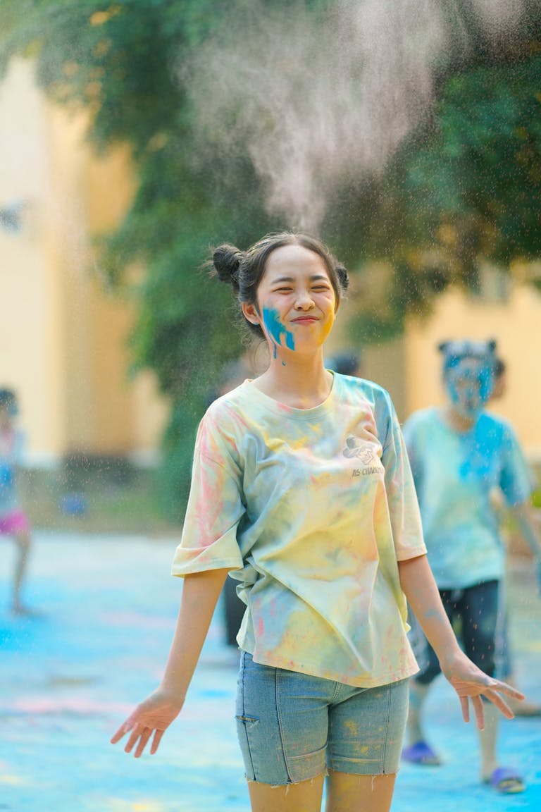 Teen enjoying the colorful celebration of Holi outdoors, exuding happiness and joy.
